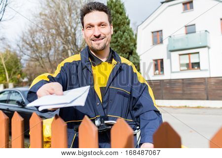 Mailman passing letters to addressee over fence
