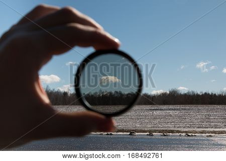 Belarus - Cloud in the blue sky frozen gaze through a polarizing filter filter in hand little white cloud fluffy cloud contrasting new field landscape snow on the field dense forest.