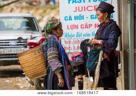 SAPA, VIETNAM - OCTOBER 29, 2012: Hmong women sell souvenirs in Sapa. The Hmongs are known for their colorful clothes and silver jewelry. Hmong women have various clothes colours and style