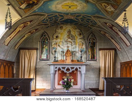 Orkneys Scotland - June 5 2012: Italian Chapel on Lamb Holm Island. Chancel and altar with bright sharp and detailed wall and ceiling paintings featuring the madonna with child angels and more