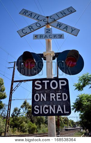 railway crossing stop sign with red lights against blue sky