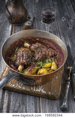 Lamb Knuckles with Potatoes in Burgundy Sauce in Casserole