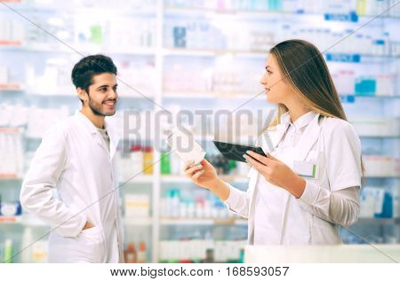 Pharmacists using digital tablet while checking medicine in pharmacy