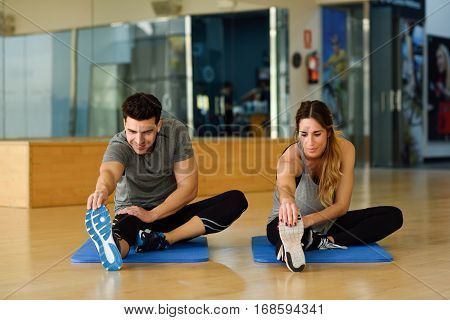 Two People Streching Their Legs In Gym.