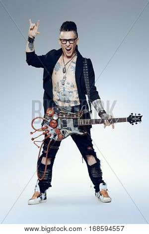 Excited rock musician is playing electrical guitar. Full length studio shot. Entertainment and musical concept. 