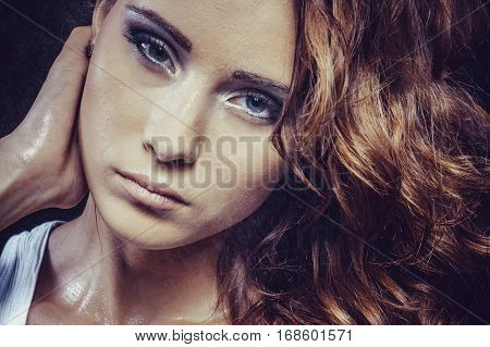 Brunette girl with beautiful make-up and wet in a spray of water close-up
