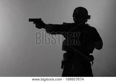 United states Marine Corps special operations command Marsoc raider with weapon aiming pistol. Silhouette of Marine Special Operator gray background