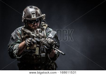 United states Marine Corps special operations command Marsoc raider with weapon. Studio shot of Marine Special Operator half-turning black background