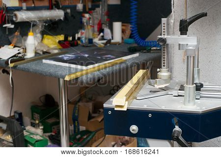Craftsman working on frame in frameshop. Professional framer hand holding frame angle. Top view.