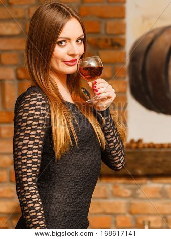 Elegant beauty lady long hair full make up wearing black dress tasting wine in rural cottage interior celler