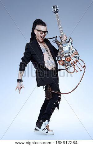 Excited rock musician is playing electrical guitar. Full length studio shot. Entertainment and musical concept. 