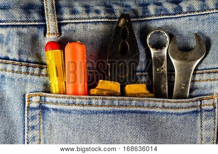 Different hand tools in a pocket of the blue jeans