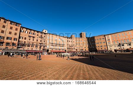 SIENA ITALY - JANUARY 5 2017: Tourists visit the ancient and medieval Piazza del Campo (Campo square) in the downtown of Siena Toscana (Tuscany) Italy