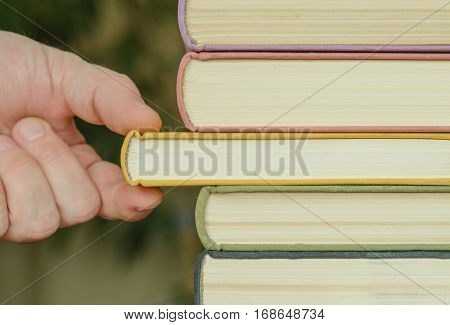 hand of man or woman takes a book on a shalf in the room or library