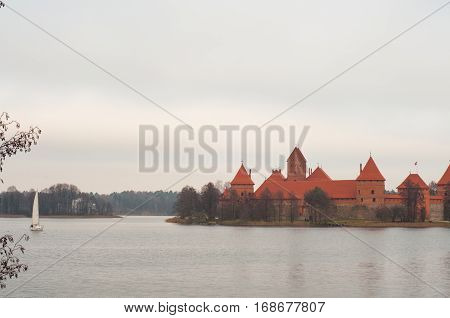 Yacht sailing at lake near Trakai Peninsula Castle Museum on the island. Village of Karaites, Lithuania, Europe. Lithuanian landmark in late autumn
