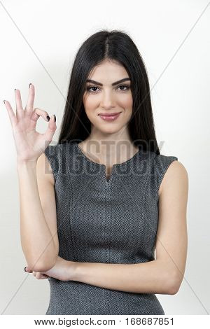 Young business woman giving the OK sign Smiling in front of a white background
