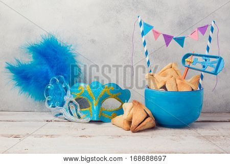 Purim celebration concept with hamantaschen cookies and carnival mask on wooden table