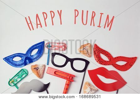 Purim celebration concept with carnival mask and photo props on white background. Top view from above