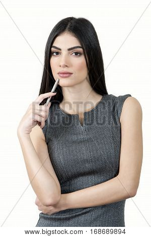 Cute business woman looking at the camera and holding a pen under her chin.