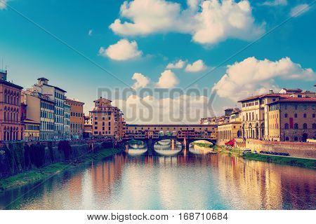 View from the river to the famous italian medieval bridge - Ponte Vecchio in Florence with blue sky and clouds, travel outdoor Italy sightseeing background