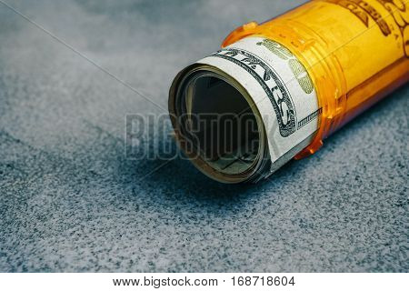 Money Bills in orange pill bottle medical concept with copyspace