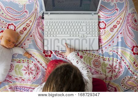 Little girl sitting in bed and playing online games in her bedroom. High angle view