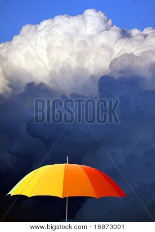 Colored umbrella against stormy sky - conceptual image.