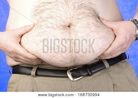 Barechested pinching his belly, mid section