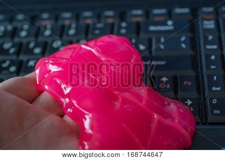 Keyboard cleaning gel in work. Hand and pink gel.