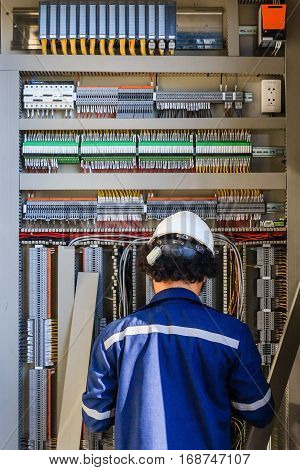 Instrument technician on the job check wiring on PLC cabinet