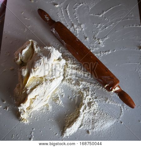 Wooden rolling pin with white wheat flour on the table. top view