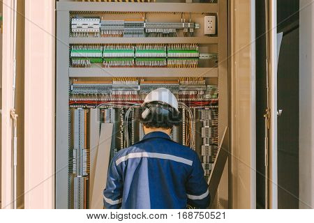 Instrument technician on the job check wiring on PLC cabinet