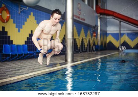 Man jumping in swimming pool. Low angle view from the swimming pool.
