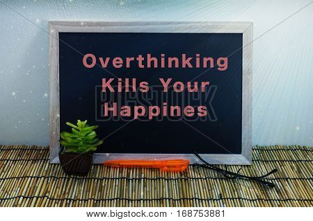 Business & creative concept,Overthinking Kills Your Happiness word on blackboard with green plant,pen & spectacle eyeglasses.