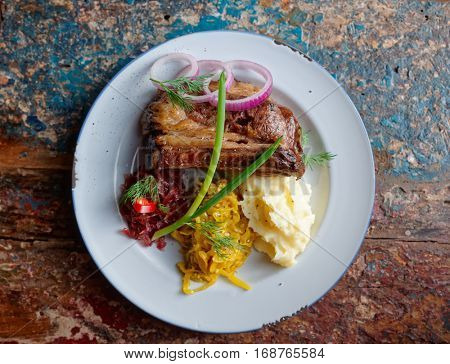 Grilled pork ribs with sauerkraut and mash potatoes on grunge peeled paint surface - hearty dish