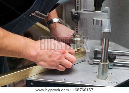 Craftsman working on frame in frameshop. Professional framer hand holding frame angle. Top view.