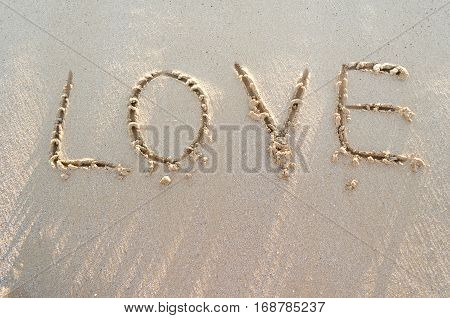 Word LOVE on a sand of beach in the morning with place for your text. Summer holiday concept. Romantic love background. Valentine's Day theme. Top view. Copy space.