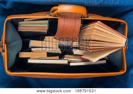 Stack of hardback books in an old suitcase with a retro effect. Back to school. Copy space. Top view.