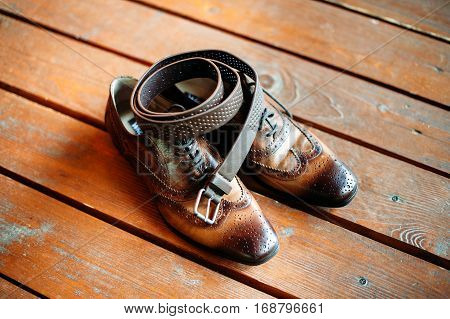 brown belt and leather shoes on a wooden floor. set of men accessories