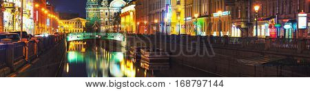 Illuminated Church on Spilled Blood with dark sky in Saint Petersburg Russia. Griboyedov canal and busy street with many cafes restaurants and shops