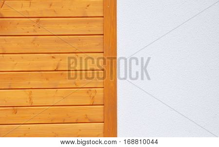 Modern house wall texture of finely slatted natural brown pine wood in a parallel pattern and white stucco used in building decor and construction on facade wall outdoor.