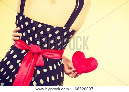 Valentine day gift proof of love romantic present concept. Woman in retro polka dot dress holding small furry red heart
