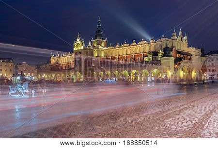 Main Market Square - Rynek Glowny - with Sukiennice - Cloth Hall - with trails of street traffic at night Poland Krakow