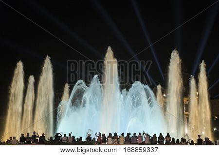 BARCELONA, SPAIN - JULY 29, 2016: Barcelona (Catalunya Spain): the Magic Fountain (Fuente Magica Font Magica) of Montjuic with plays of colorful lights at evening and people in silhouette watching at the show