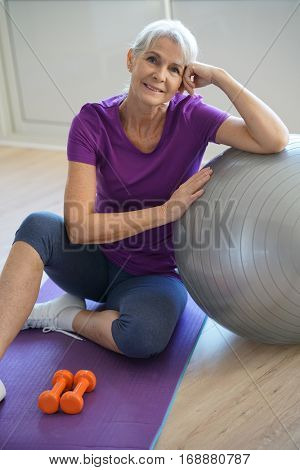 Senior woman sitting by fitness ball