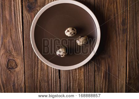 Quail eggs in a brown plate on a wooden table. Rustic Style. Eggs. Easter photo concept. Copyspace