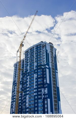 Crane and building construction site against blue sky.