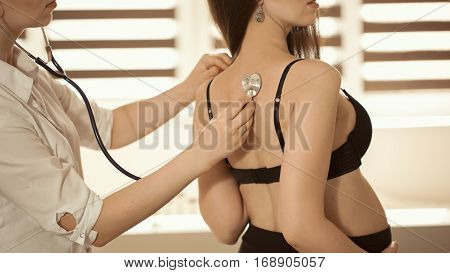Friendly Female Medicine Doctor Holding Stethoscope And Listening To Pregnant Woman Standing For Enc