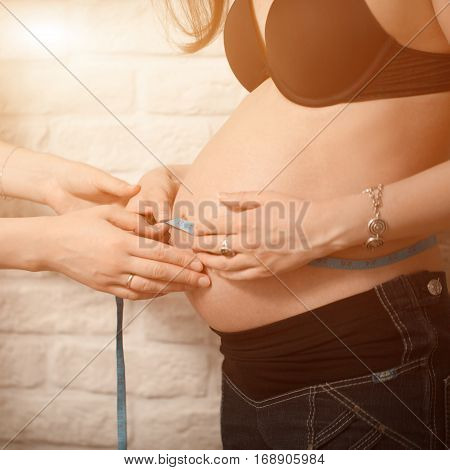 Friendly Female Medicine Doctor Holding Centimeter Tape And Listening To Pregnant Woman Standing For