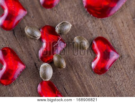 Macro detail of marijuana seeds over wood background with red hearts - cannabis growing concept